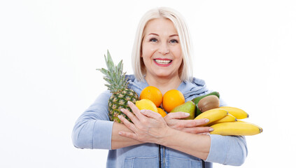 Happy middle aged woman with blond hair and beautiful smile holds products from the store in paper bag of vegetables in her hands for a healthy diet with vitaminswith.