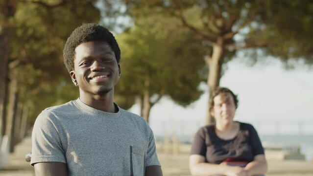 Portrait of happy African American man using wheelchair with female friend in background. Man with disability concept