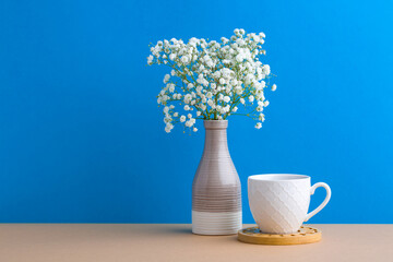 Beautiful small white flowers in modern vase set on wood table wall background with copy space, soft tone still life