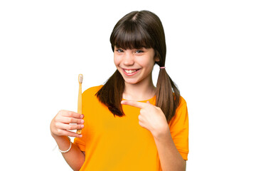 Little caucasian girl brushing teeth over isolated background and pointing it