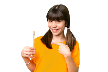 Little caucasian girl brushing teeth over isolated background and pointing it