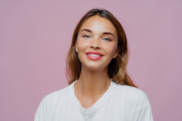 Close up shot of feminine girl smiles gently at camera, wears minimal makeup, has healthy skin,...