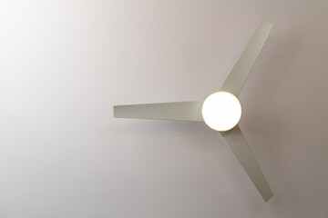 Isolated white ceiling fan with light turned on, view from below