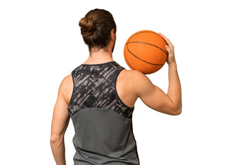 Young handsome man isolated on green chroma background playing basketball in back position