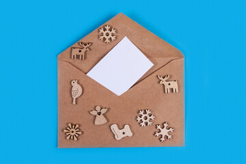 Christmas composition. Wooden Christmas decorations and envelope on blue background.