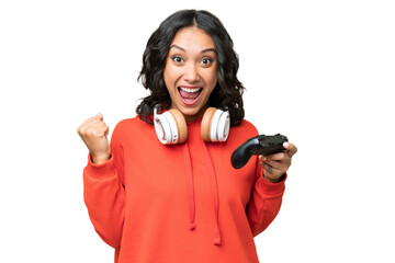 Young Argentinian woman playing with a video game controller over isolated background celebrating a victory in winner position © luismolinero