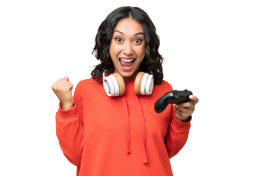 Young Argentinian woman playing with a video game controller over isolated background celebrating a victory in winner position