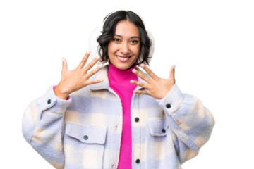 Young Argentinian woman wearing winter muffs over isolated background counting ten with fingers
