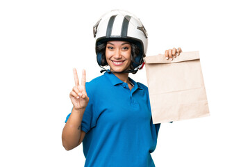 Young Argentinian woman taking a bag of takeaway food over isolated background smiling and showing victory sign