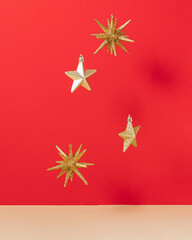Golden star shaped ornament levitate on red and beige background. Aesthetic vibrant New Year concept. Minima Christmas holiday idea. 