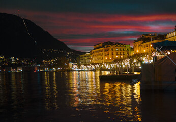 fiery sky of winter sunset, bright reflections on the water of the lake. Lugano, Switzerland