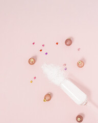 Champagne glass decorated with snow and  baubles on bright pastel pink background. Creative Christmas or New Year party concept. Minimal winter holiday season idea.