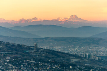 top view of tbilisi at dusk and mountain peaks on the horizon