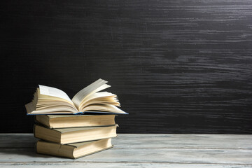 Vintage old hardback books, diary, fanned pages on wooden desk table and grunge background Daylight. Books stacking. Back to school. Copy Space. Education background.