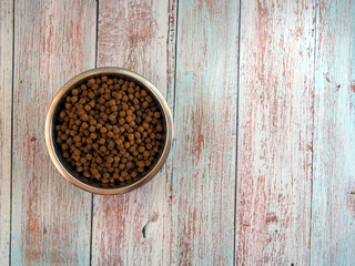 Dog food in a metal bowl on wooden  background