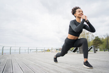 The running coach is wearing a tracksuit in sneakers. A sporty female runner uses a fitness watch for training.