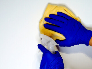 A hand in a blue glove washes a white surface with a white vinegar