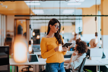 Female boss, manager executive posing in a modern startup office while being surrounded by her coworkers, team.