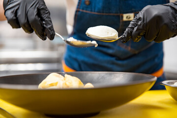 chef cooking food. Chef's hands in gloves cooking crepe pancake on plate in kitchen