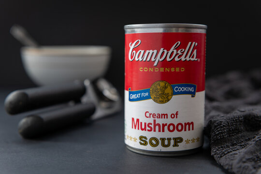 London. UK- 05.16.2021: a tin of canned Campbell's cream of mushroom soup on a table with a dark background.