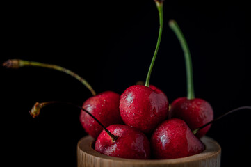Collection of fresh cherries on a dark background, dynamic shot with action, splash, water drops and bokeh. Fresh fruit floating or levitating shotwith water droplet