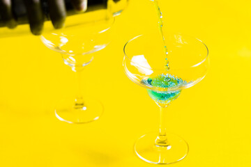 Bartender pouring Blue Lagoon  curacao syrup mixed with vodka and lemonade cocktail from a shaker into a glass of alcohol