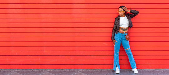 fashionable modern urban woman on the street with red wall
