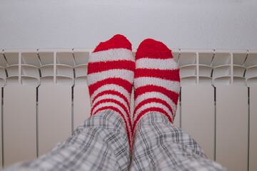 feet in striped socks on the heating radiator at home