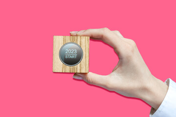 Concept of the start of the new 2023. Wooden block with a start button, in a female hand, on a...