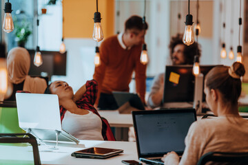 Group of multi-ethnic colleagues working on desktop computers, laptop and sharing their ideas in a modern office space.Young influencers work on online marketing projects.