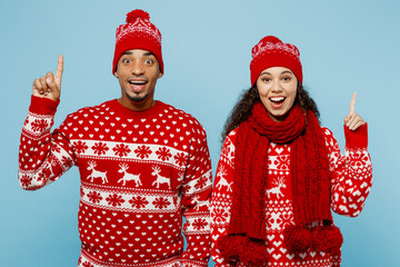 Merry young couple friends two man woman wear red Christmas sweater Santa hat posing hold index...