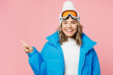 Snowboarder fun woman wear blue suit goggles mask hat ski padded jacket point index finger aside on area isolated on plain pastel pink background Winter extreme sport hobby weekend trip relax concept