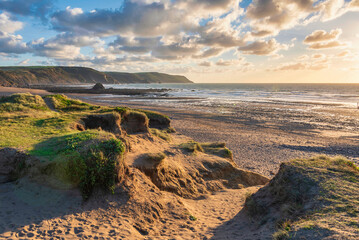 Stunning Summer sunset landscape image of Widemouth Bay in Devon England with golden hour light on beach