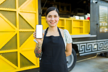 Latin woman working at the food truck showing delivery app orders