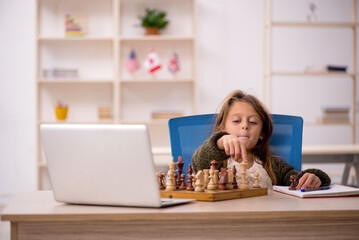Young little girl playing chess at home