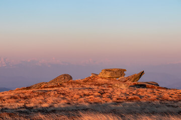 Scenic view of rock formation and Karawanks mountains at sunrise seen from alpine meadow at...