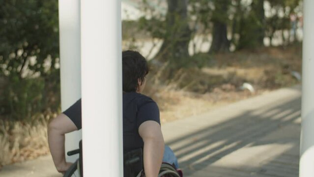 Young woman with disability wheeling in park. Caucasian woman using wheelchair and walking outdoors. Woman with disability concept