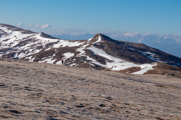 Woman hiking on frozen alpine meadow from Ladinger Spitz to Gertrusk, Saualpe, Lavanttal Alps,...