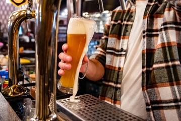 bartender's hands pouring craft beer from a tap into a glass in bar