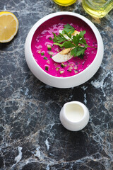 Cold beetroot soup with kefir served in a white bowl on a black marble background, vertical shot with space, high angle view