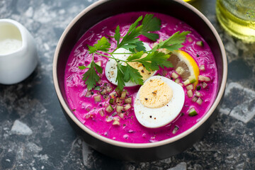 Bowl of cold beetroot soup served with hard-boiled egg and fresh parsley, middle close-up on a...