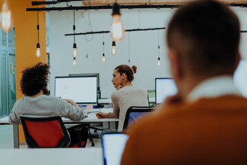 Two colleagues working on a project in modern startup offices. Guy with afro haircut and a female blonde employee working at the office.