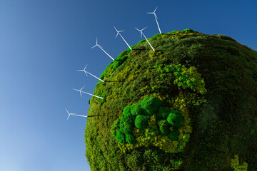 Model of the green planet Earth from moss with wind turbines. Symbol of sustainable development and renewable energy