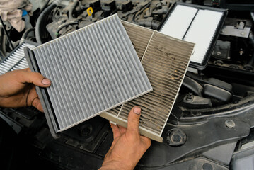 A new car air filter and an old one with garbage in the hands of a man. Comparison and preventive...