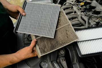 A new car air filter and an old one with garbage in the hands of a man. Comparison and preventive...