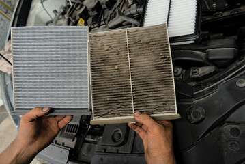 A new car air filter and an old one with garbage in the hands of a man. Comparison and preventive...