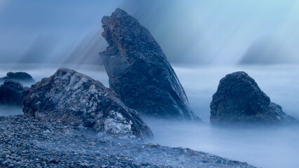 Water rolling over rocks at coastline mist long exposure scenic background