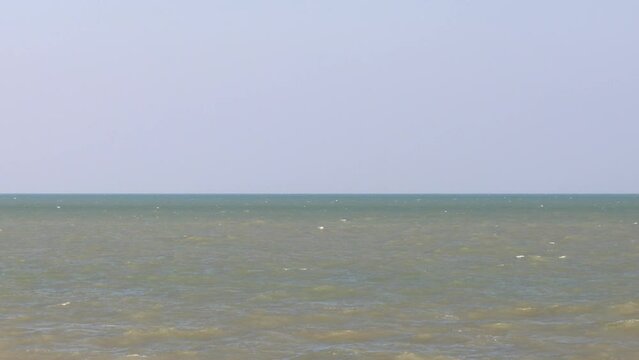 The simplicity of the sky contrasts with the dark horizon.  when you can see the sea color in separate layers when approaching the shore and the color is not bright  with waves so strong that they spl