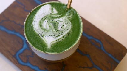Close-up of a mug of matcha tea with green froth. A cup of hot macha with vegetable milk, an alternative to coffee. Delicious and invigorating matcha green tea drink for energy for the whole day.