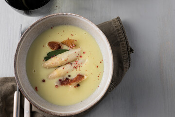 Delicious creamy asparagus soup with some ham, asparagus tips, sage and a bit of pink pepper.